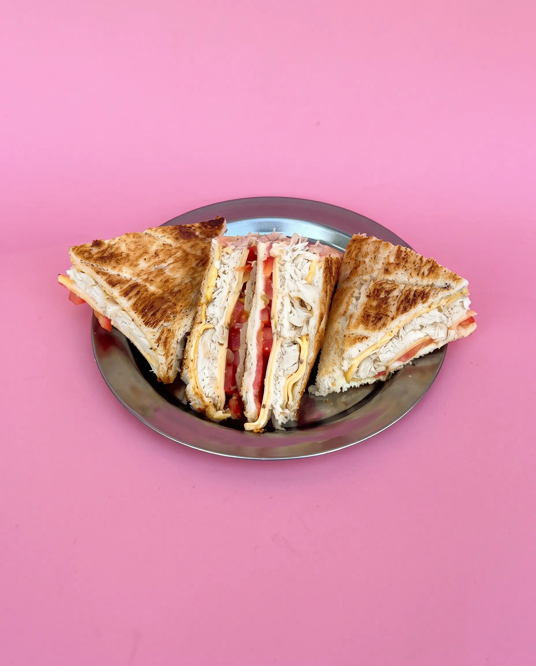 Sándwich tostado de pollo, tomate y queso ahumado