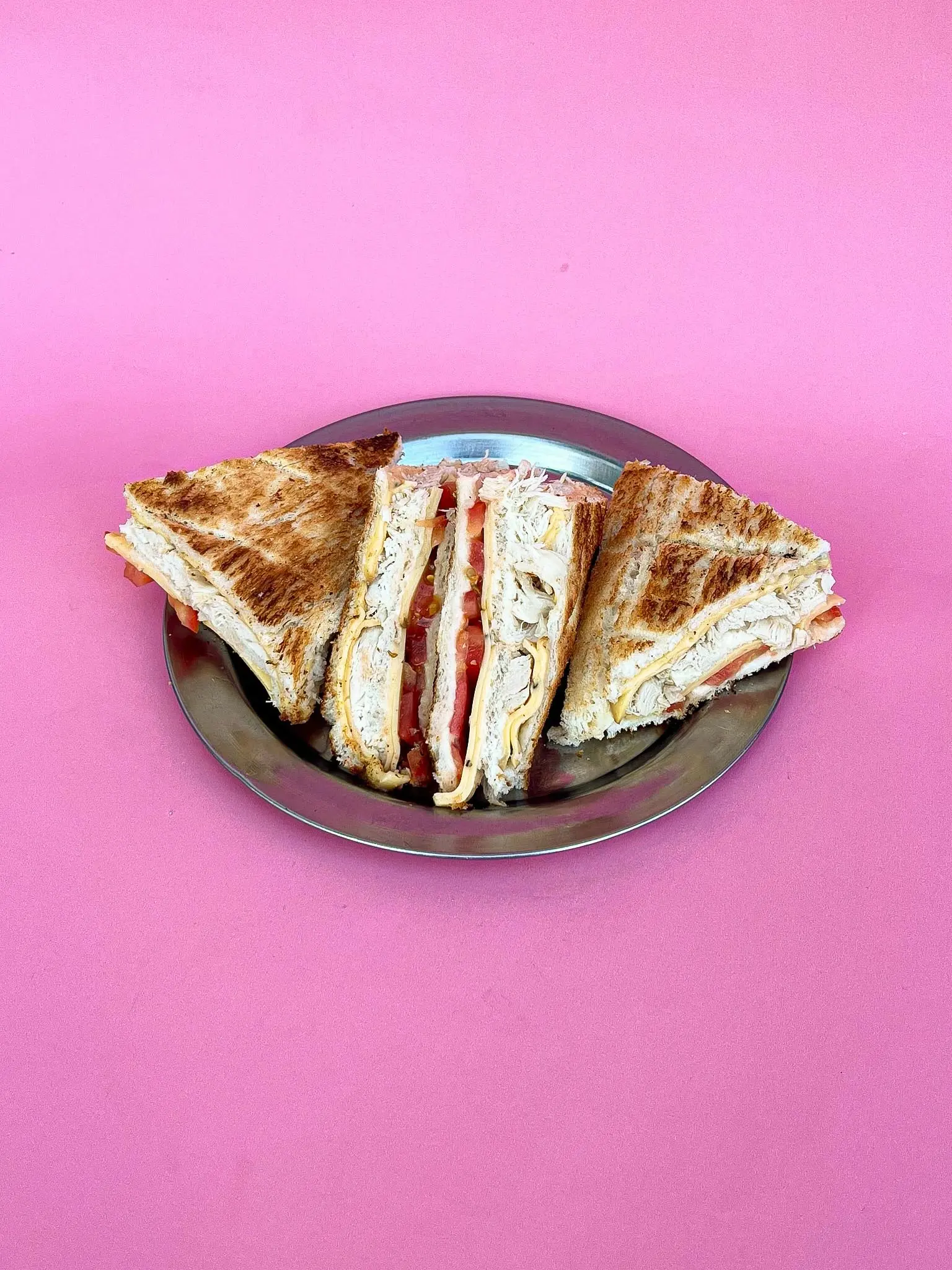 Sándwich tostado de pollo, tomate y queso ahumado