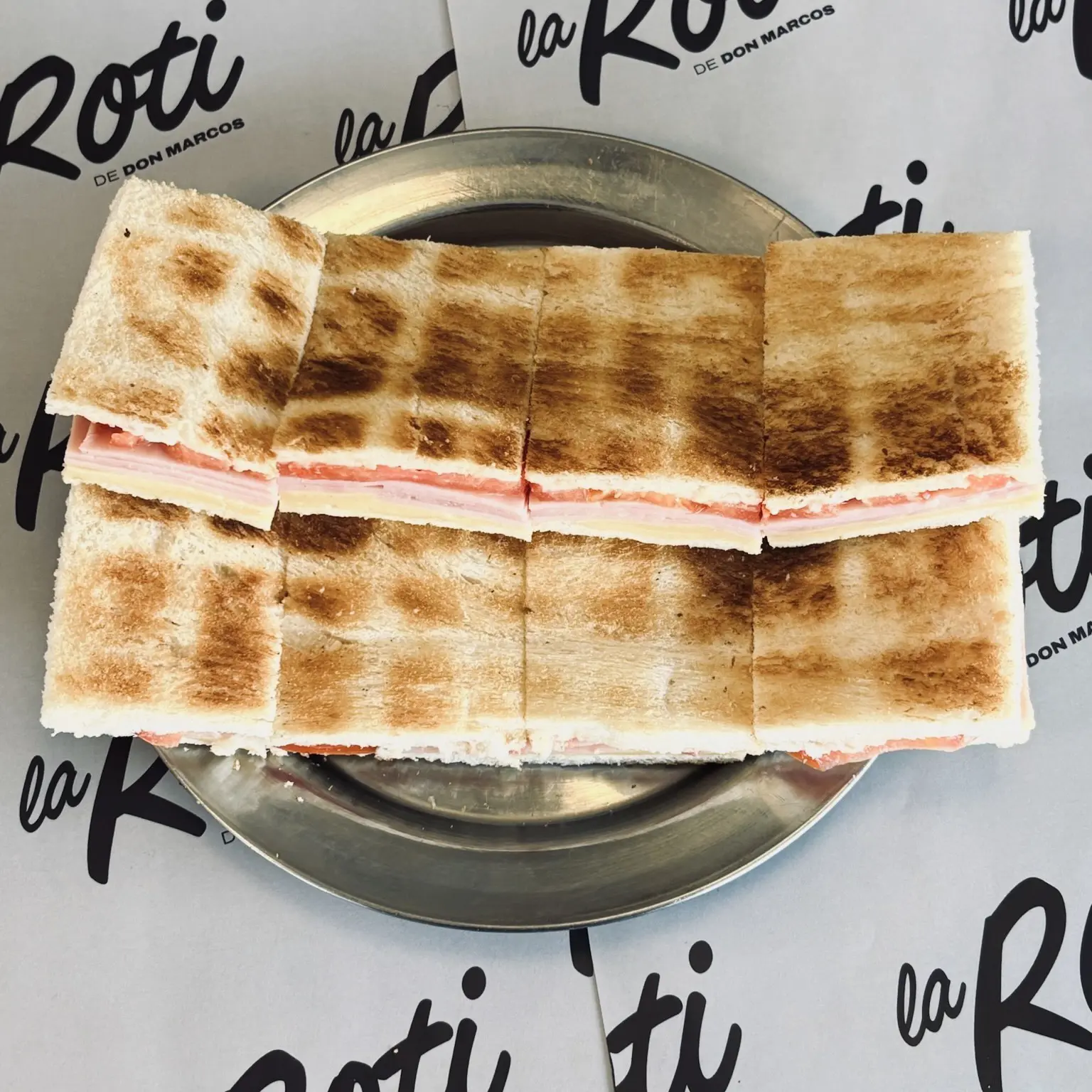 Sándwich tostado de pollo, tomate y queso ahumado